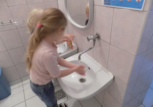 Gabrysia i Lilianka ćwiczą prawidłowe mycie rąk przy umywalce.